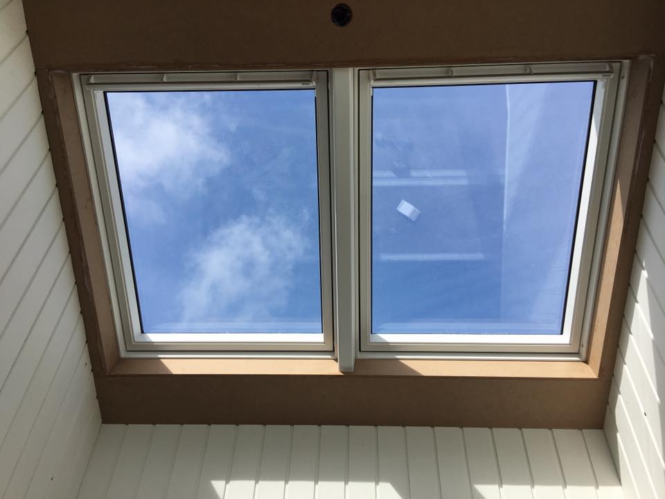 To ovenlysvinduer med blå himmel udenfor