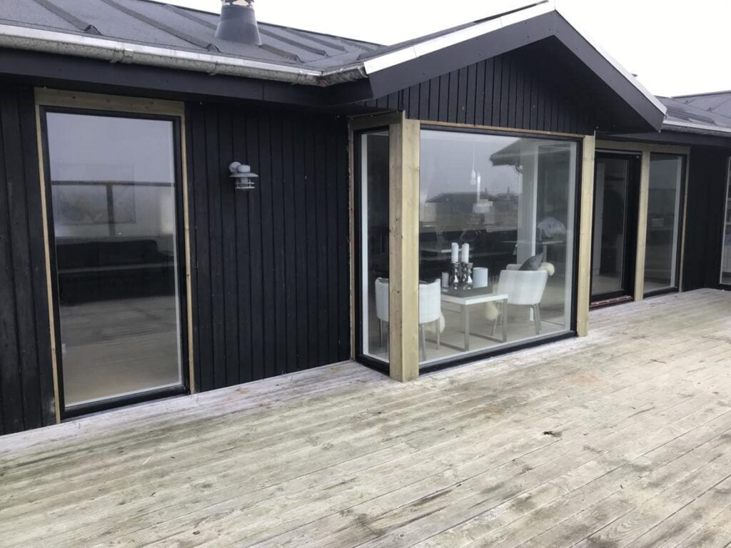 Sort træhus med store vinduer og terrasse